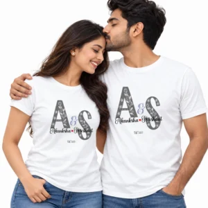 Indian couple wearing matching white personalized T-shirts with gray floral A and S initials, Akanksha and Sushant names, a red heart, and Est 2025.