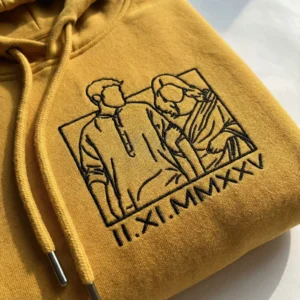 Close-up view of personalized line-art photo embroidery on mustard couple hoodie