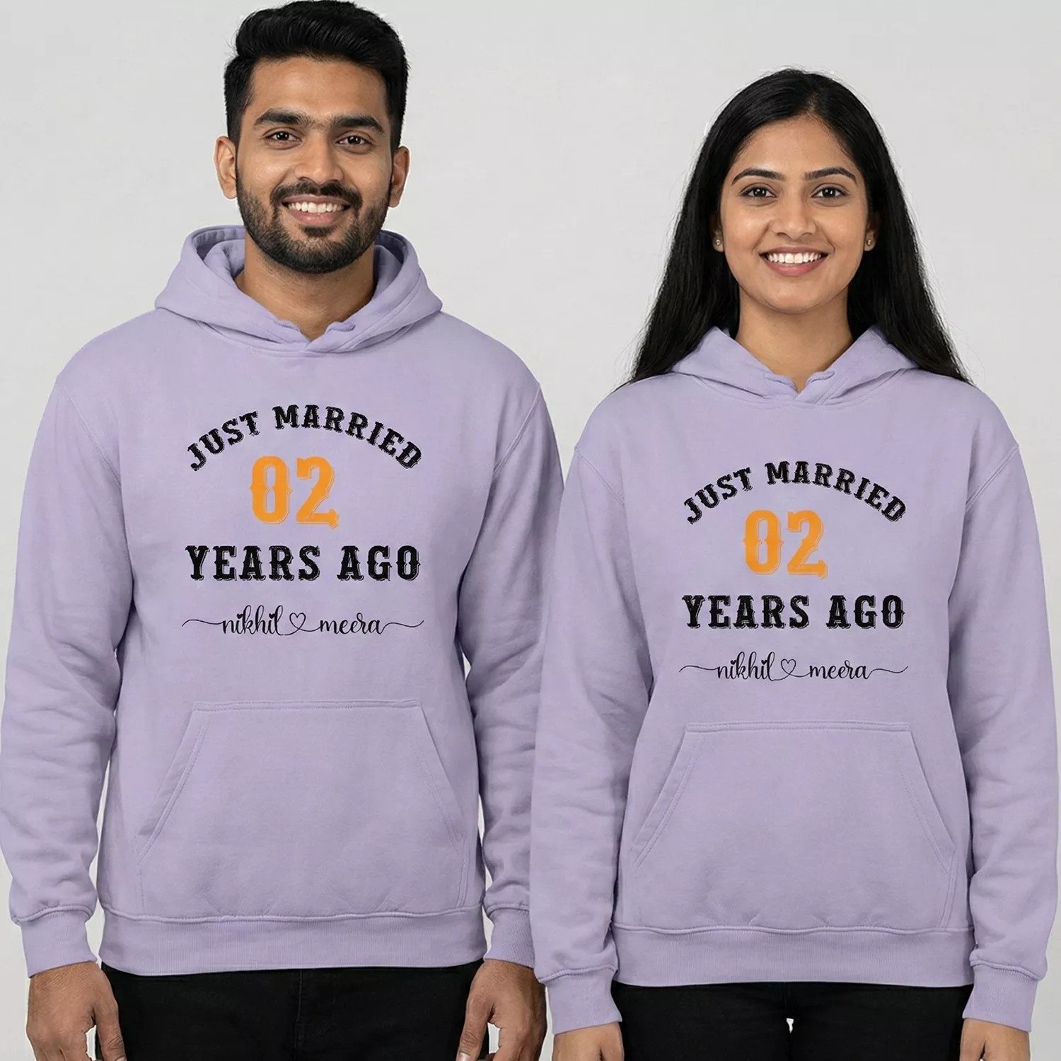 Couple wearing custom 2nd anniversary matching couple hoodies with “Just Married 02 Years Ago” printed and personalized names.