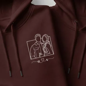 Close-up view of custom embroidered couple photo line-art design on maroon hoodie