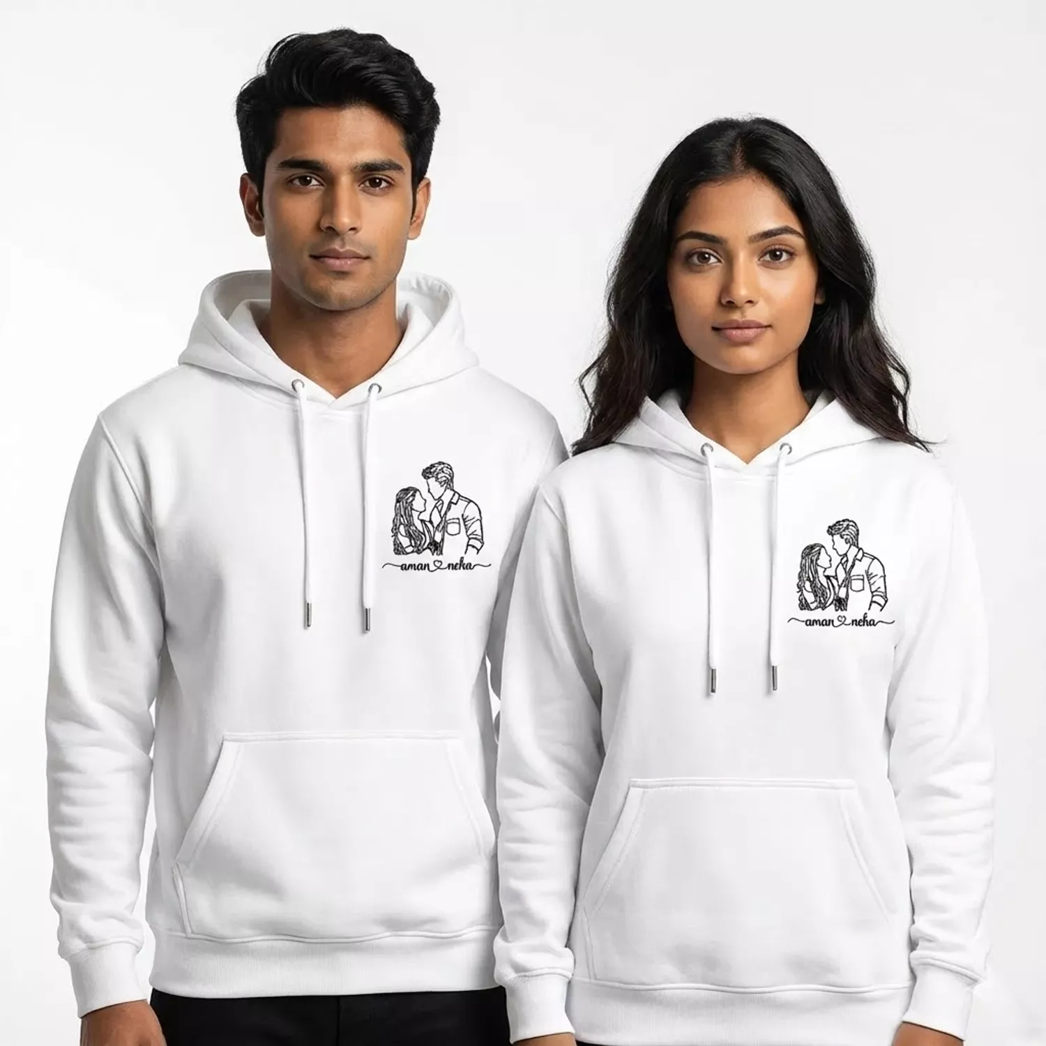 Couple wearing custom line-art embroidered hoodies with personalized portrait and names on white hoodies