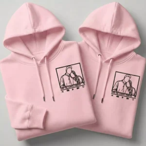 Pink couple hoodies with custom line-art portrait embroidery and matching minimalist design.