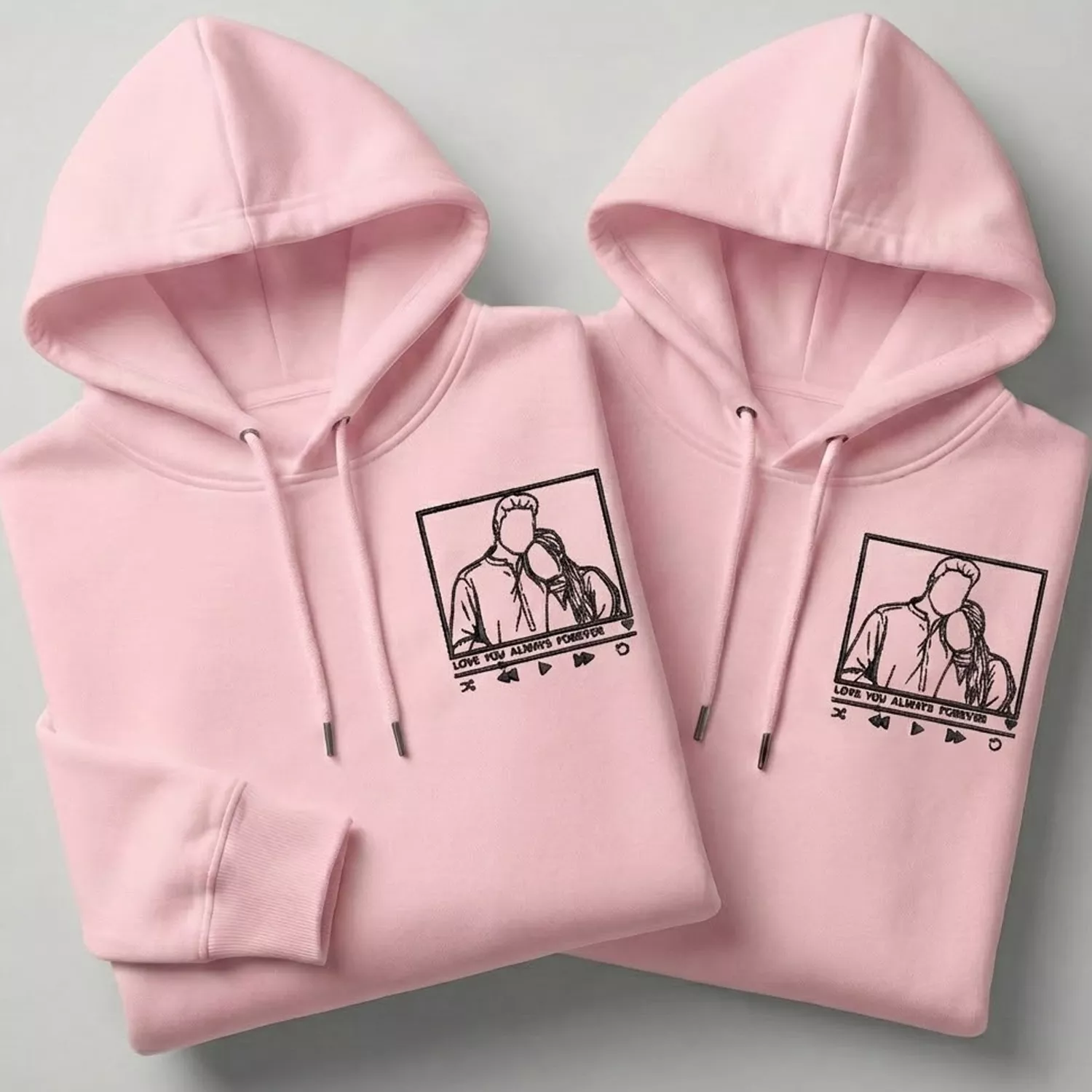Pink couple hoodies with custom line-art portrait embroidery and matching minimalist design.