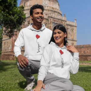 Couple wearing custom name couples hoodie combo with red heart design in an outdoor photoshoot