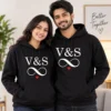 Personalized his and her initials couple hoodies in black with infinity design and red heart, worn by a couple