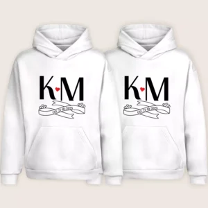 Matching couple hoodies with KM initials, heart symbol, and EST. 27-10-2025 printed on white personalized hoodies.
