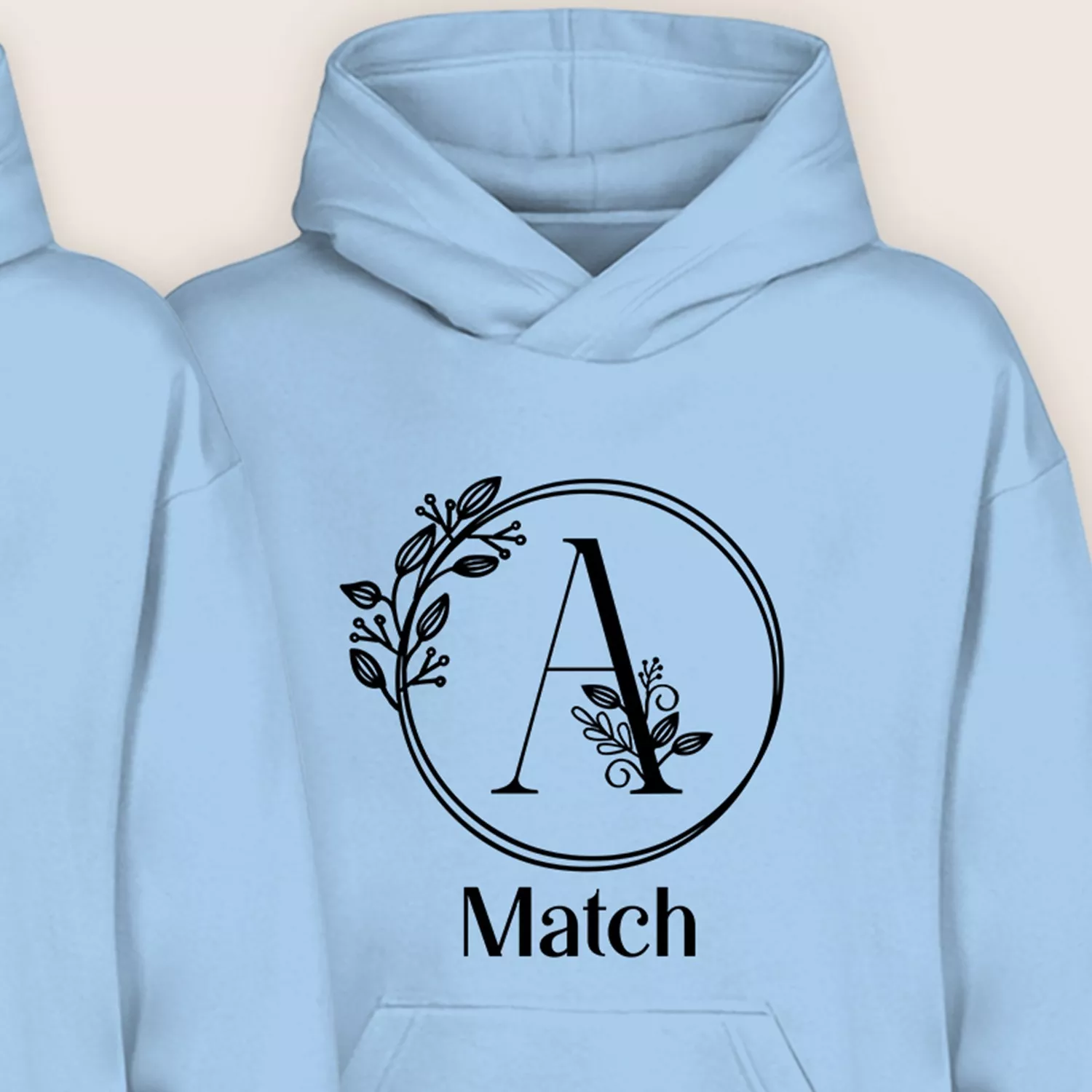 Close-up of light blue personalized hoodie with floral monogram initial A and “Match” text.