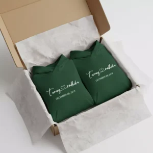 Two green matching couple name hoodies with personalized names and date neatly packed inside a gift box.