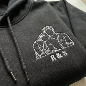 Close-up of minimal photo outline embroidery on black couple hoodie with R & S initials