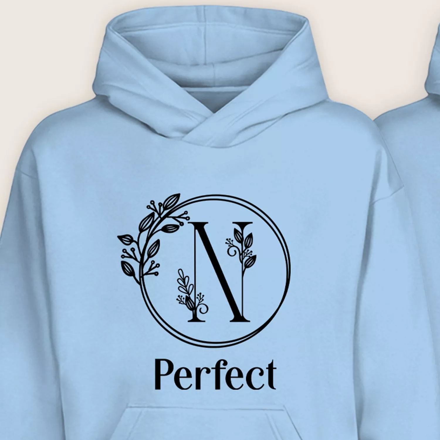 Close-up of light blue personalized hoodie with floral monogram initial N and “Perfect” text.