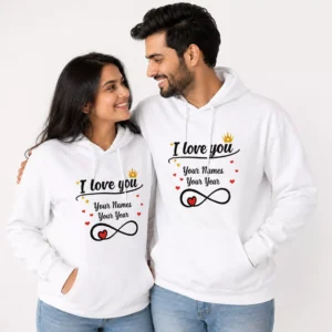 Couple wearing matching white personalized I Love You hoodies with custom names, year design, hearts, crown accents, and infinity heart graphic for anniversary gifting.