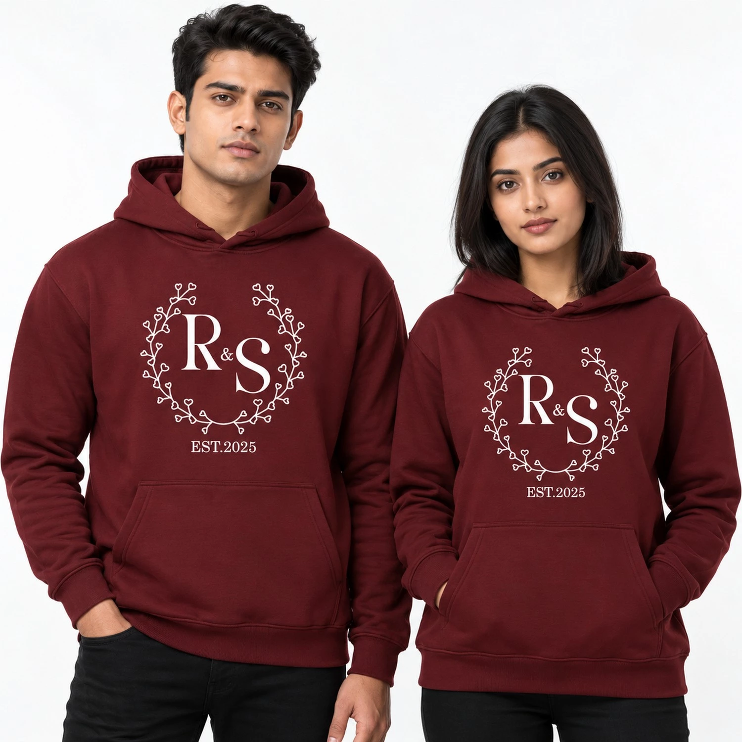 Maroon personalized couple hoodies with white R and S initials, heart vine wreath, and EST. 2025 text.