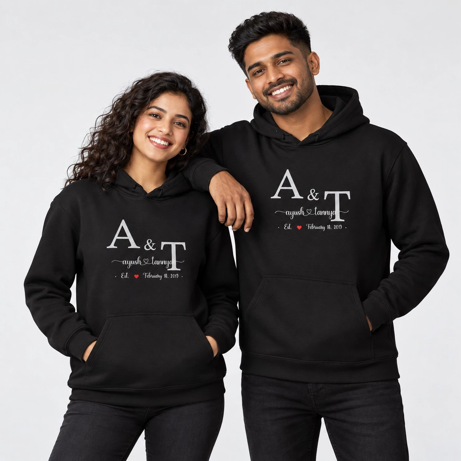 Black personalized couple hoodies with large A and T initials, Ayush and Tannya names, a red heart, and February 14 2013 date.