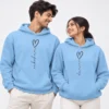 Light blue personalized name couple hoodies with vertical black script names ending in outlined heart designs.
