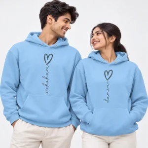 Light blue personalized name couple hoodies with vertical black script names ending in outlined heart designs.