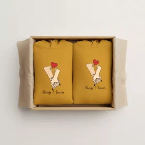 Gift box with two mustard yellow personalized couple hoodies featuring hand-holding illustration and customizable names