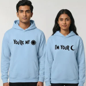 Couple wearing light blue matching hoodies with “You’re My Sun” and “I’m Your Moon” printed in black text