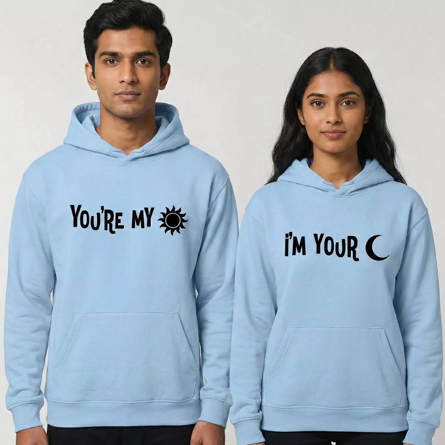 Couple wearing light blue matching hoodies with “You’re My Sun” and “I’m Your Moon” printed in black text