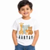 Smiling toddler boy wearing a white personalized kids T-shirt featuring cartoon giraffe, elephant, fox and bear illustrations with the name AARYAV in bold black uppercase letters.