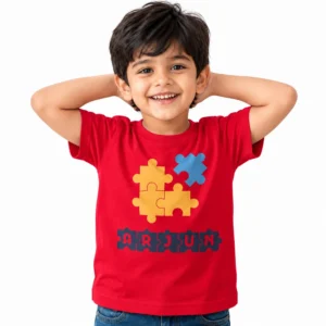 Smiling young boy wearing a red personalized kids T-shirt featuring yellow and blue jigsaw puzzle pieces above the name ARJUN displayed in dark puzzle-shaped lettering.