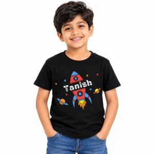Smiling young boy wearing a black personalized T-shirt featuring a red and blue rocket, colorful planets, stars and the name Tanish in white distressed-style lettering.