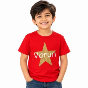 Smiling young boy wearing a red personalized kids T-shirt featuring a large glitter-effect golden star with the name Varun printed across it in white lettering.