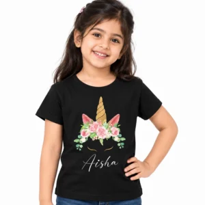 Young girl wearing a black personalized kids T-shirt featuring a golden unicorn horn, pink floral crown, unicorn ears, and white cursive name Aisha.