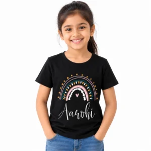 Smiling young girl wearing a black personalized kids T-shirt featuring a decorative pastel rainbow with pink, teal, white and golden accents and the name Aarohi in white cursive lettering.
