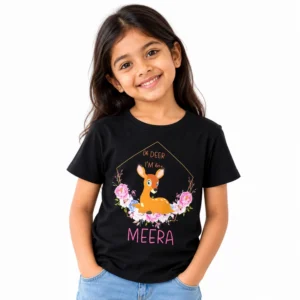 Smiling young girl wearing a black personalized T-shirt featuring a cute brown baby deer surrounded by pink flowers, Oh Deer I'm Here lettering, and the name Meera in pink.