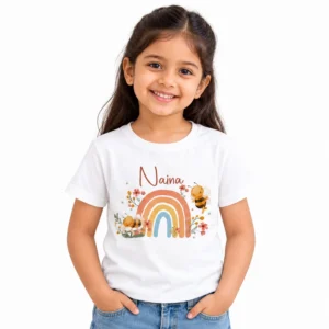 Young girl wearing a white personalized T-shirt featuring the name Naina above a pastel rainbow decorated with cute bees, small flowers and green leaves.