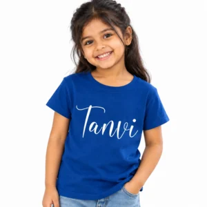 Smiling young girl wearing a royal blue personalized kids T-shirt featuring the custom name Tanvi in large white cursive lettering on the front.