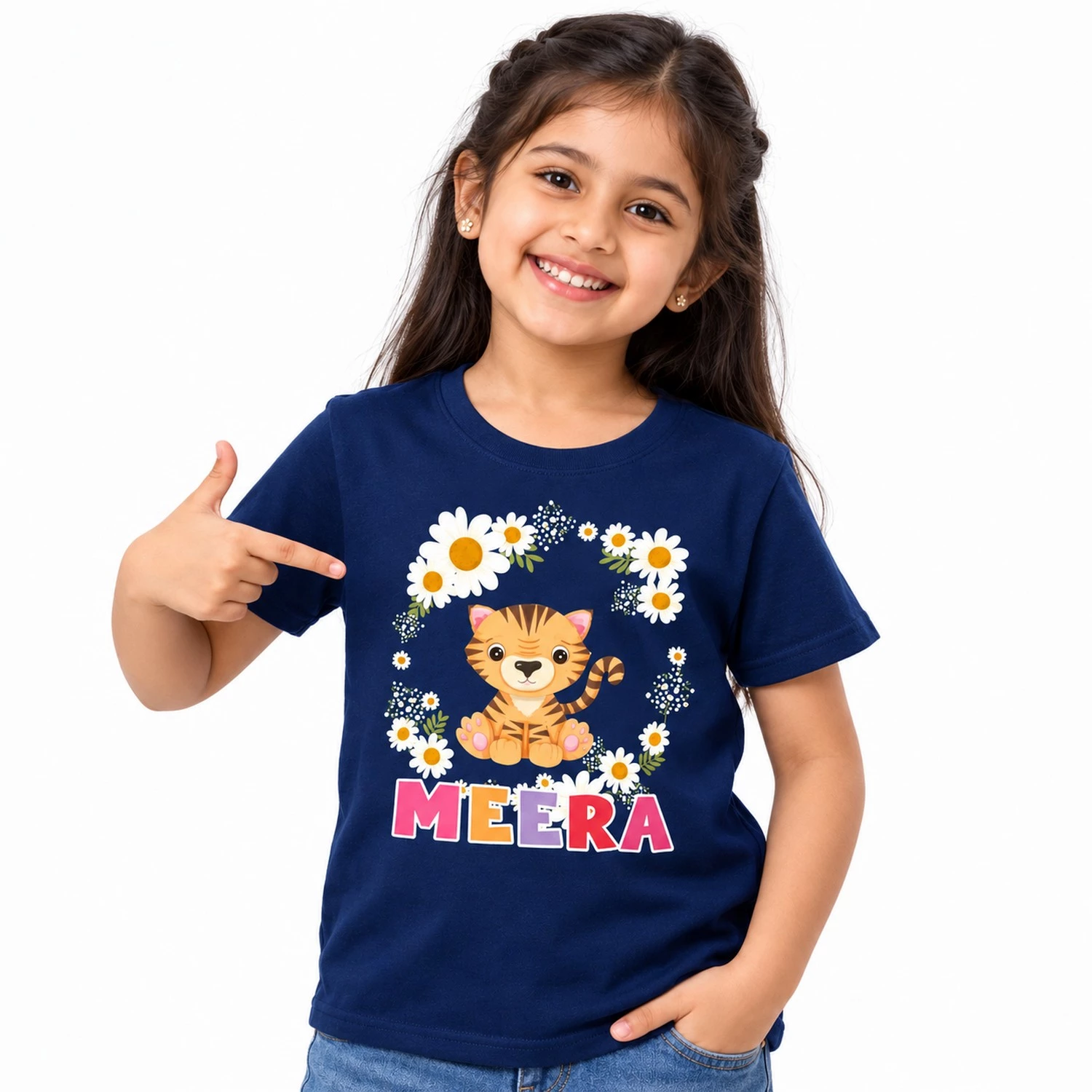 Young girl wearing a navy blue personalized kids T-shirt with a cute orange tiger cub surrounded by white daisies and colorful custom name MEERA.