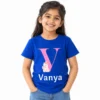 Young girl wearing a royal blue personalized kids T-shirt featuring a large pink letter V, small pastel unicorn illustration, and white custom name Vanya.