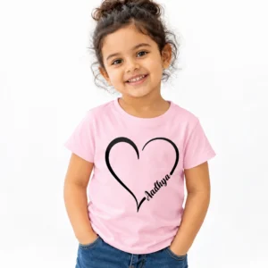 Smiling young girl wearing a light pink personalized kids T-shirt featuring a large black heart outline with the name Aadhya in elegant cursive lettering.