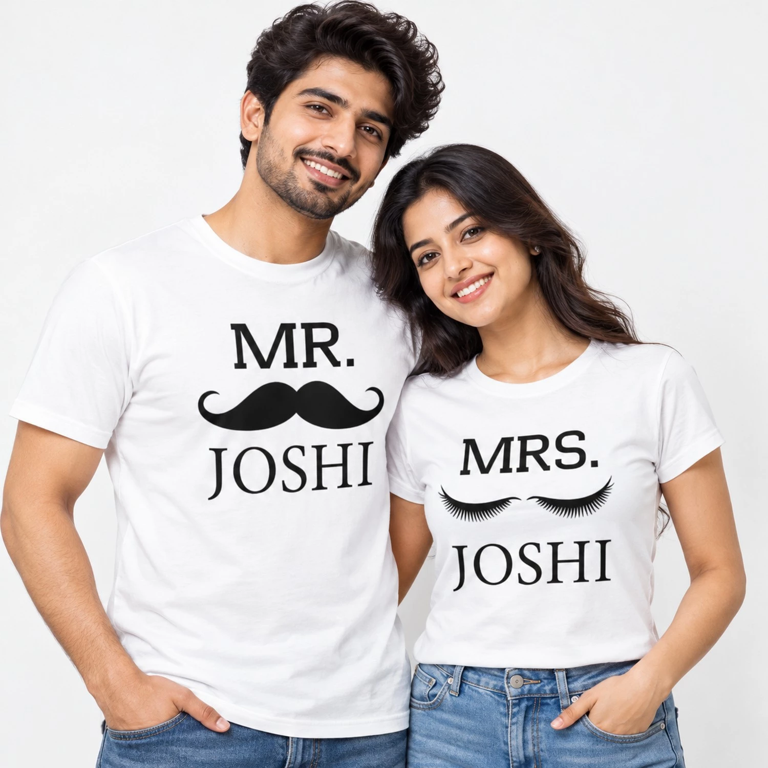 Indian couple wearing matching white personalized couple T-shirts with black MR. JOSHI mustache artwork on the men's shirt and MRS. JOSHI eyelash artwork on the women's shirt.
