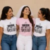 Bride wearing a pink Bride Squad T-shirt with friends in matching white Bride Squad shirts with heart and arrow design