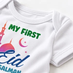 Close-up of a white First Eid baby romper showing the ribbed neckline, sleeve stitching, cotton texture, and part of the personalized Eid print.