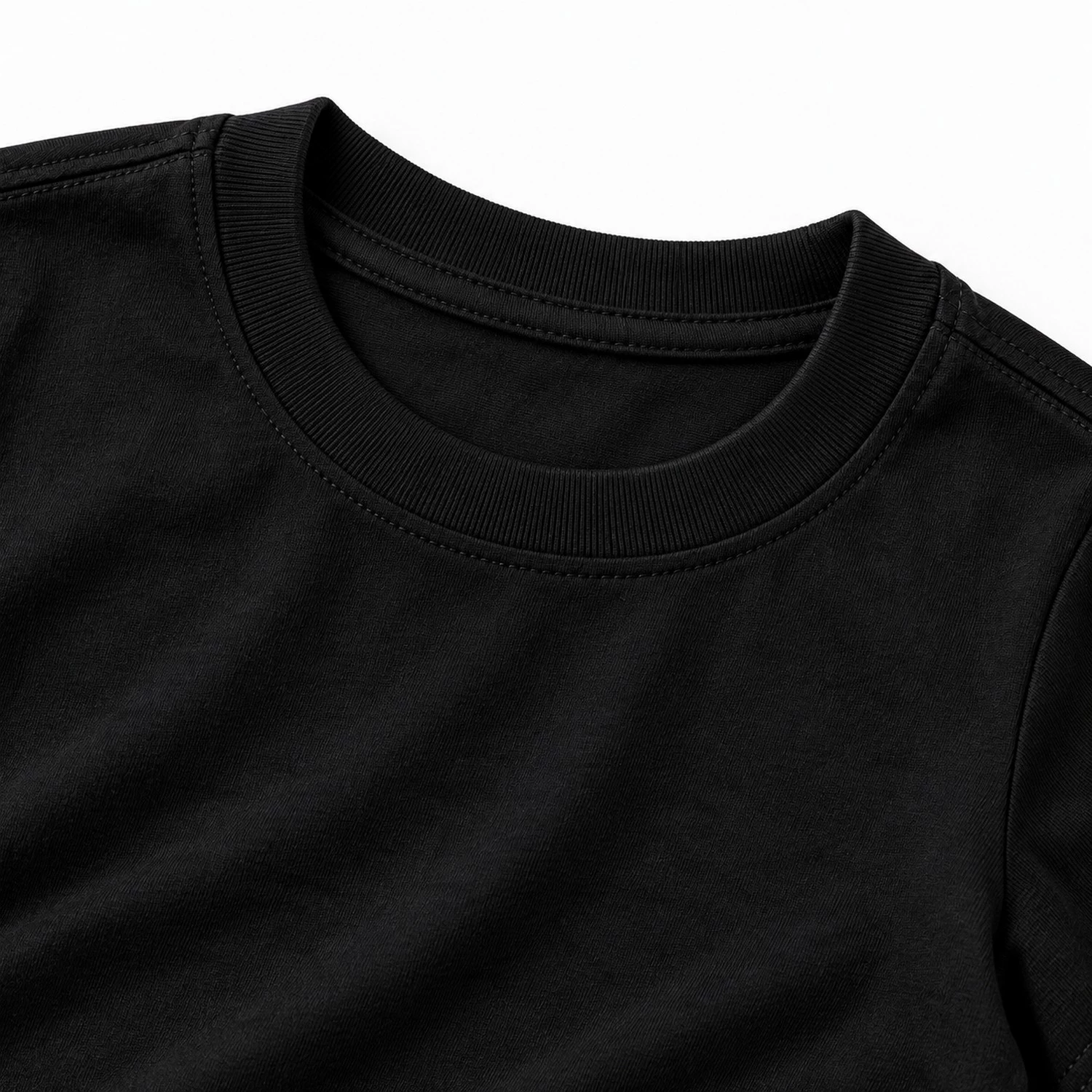 Close-up of black kids t-shirt fabric and ribbed crew neckline showing stitching and cotton texture.