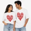 Couple wearing matching white oversized unisex T-shirts with red Manifest More Love heart graphic