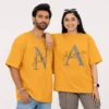 Couple wearing mustard oversized T-shirts personalised with large N and A initials and custom Nakul and Ahana names