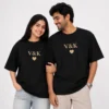 Couple wearing matching black oversized unisex T-shirts with personalised V and K initials and gold heart