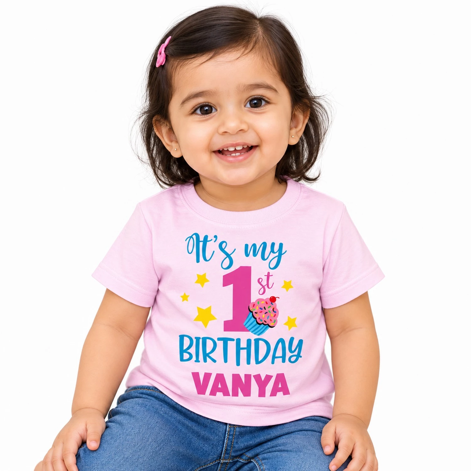 Indian toddler wearing a pastel pink personalized 1st birthday kids t-shirt with βItβs my 1st Birthday Vanyaβ print on a clean white background