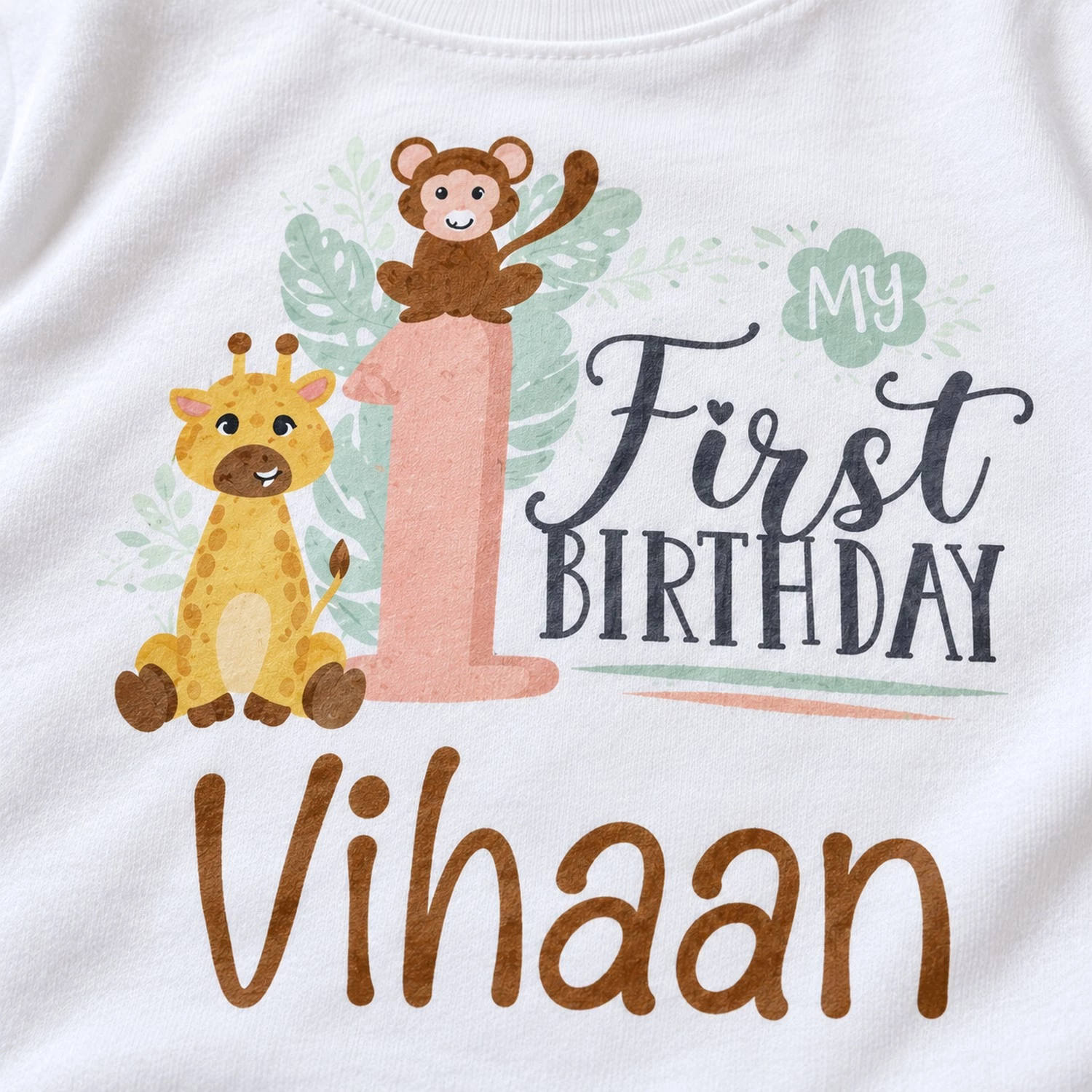 close-up of personalized 1st birthday t-shirt print showing my first birthday text, jungle animals, number 1, and the name Vihaan