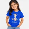 Royal blue personalized girls' T-shirt featuring a smiling cartoon giraffe above pink flowers and the name Aisha printed in white cursive lettering.
