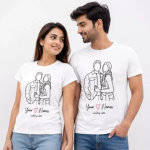 A smiling couple wearing matching white personalized T-shirts with custom couple line art, names, heart design, and wedding date printed on the front.