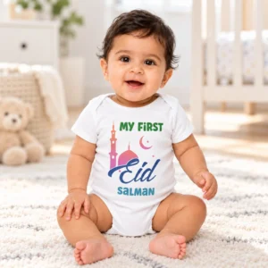 Smiling baby wearing a white personalized First Eid romper with the name Salman while sitting in a bright neutral nursery.