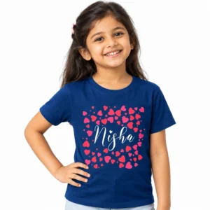 Smiling Indian girl wearing a royal blue personalized kids T-shirt featuring the name Nisha in white cursive lettering surrounded by bright pink and red heart graphics.