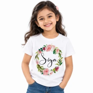 Smiling young girl wearing a white personalized kids T-shirt featuring the name Siya in black cursive lettering surrounded by a circular wreath of pink roses, green leaves, and delicate flowers.