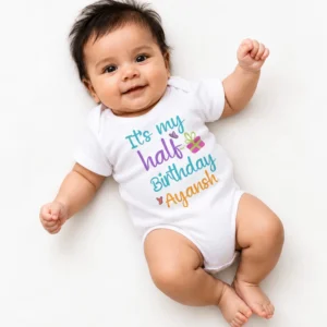 Smiling baby wearing a white personalized half birthday baby romper printed with βItβs my half Birthday Ayanshβ in colorful lettering.