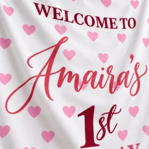 Close-up of Amaira’s personalized kids birthday tapestry banner showing crisp pink script, burgundy 1st birthday text, hearts and soft fabric texture.
